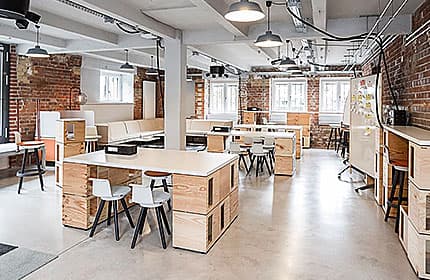 Open Space der wunderbar Plagwitz mit flexiblen Holztischen, Sitzgruppen und Backsteinwänden
